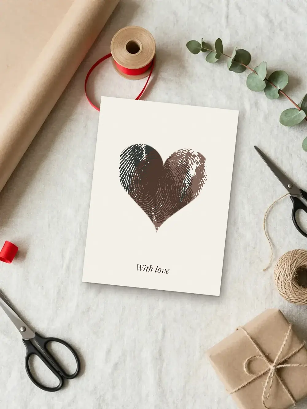 Christmas gift mockup: a fingerprint heart made from two real ink prints, printed and laid on a gift-wrapping table with kraft paper and ribbon